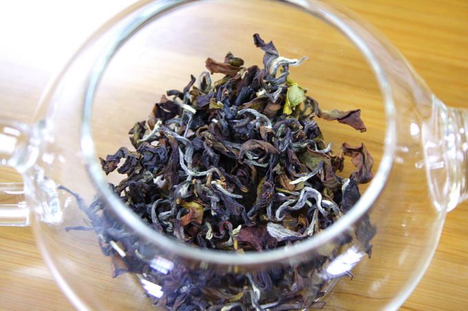 The photo shows the tea leaves inside the tea pot. The tea leaves almost covers the bottom part of tea pot. 