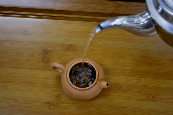 Pour in the hot water. When pouring water, move the kettle upwards and downwards which is good as it will agitate the tea leaves. You can feel the aroma from the upcoming steam.