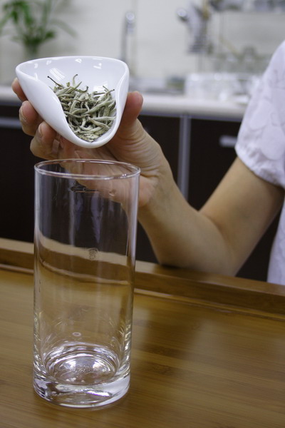 Place tea leaves into the long glass.