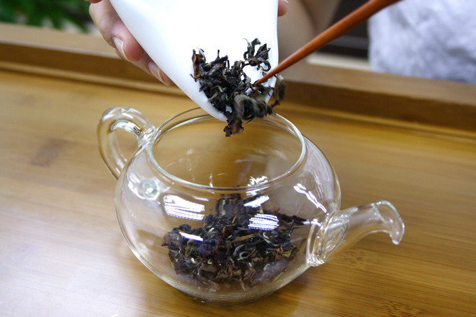 Place the tea leaves into the warmed tea pot. It is important not to touch the tea leaves in order to avoid contamination of odor.